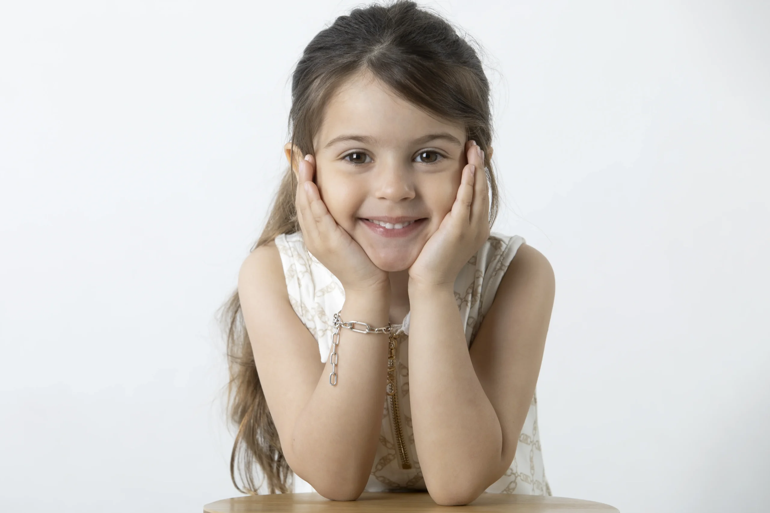 Bambina di 5-6 anni sorridente con mani sul viso durante un servizio fotografico in studio a Milano, esempio di shooting riuscito con bambini collaborativi